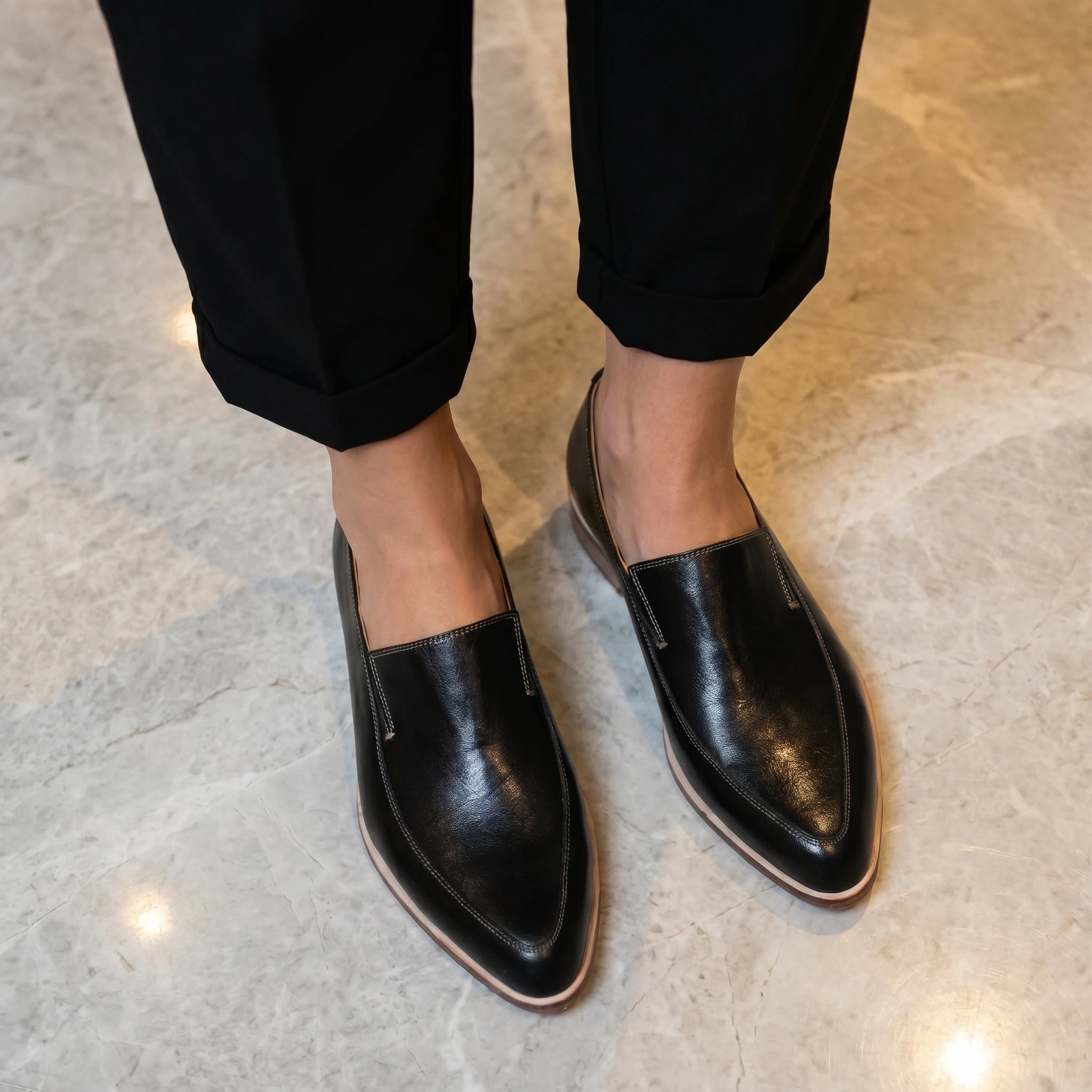 Back view of a model wearing women's sleek orthopedic loafers in Black, showing the refined construction and design against a neutral background.