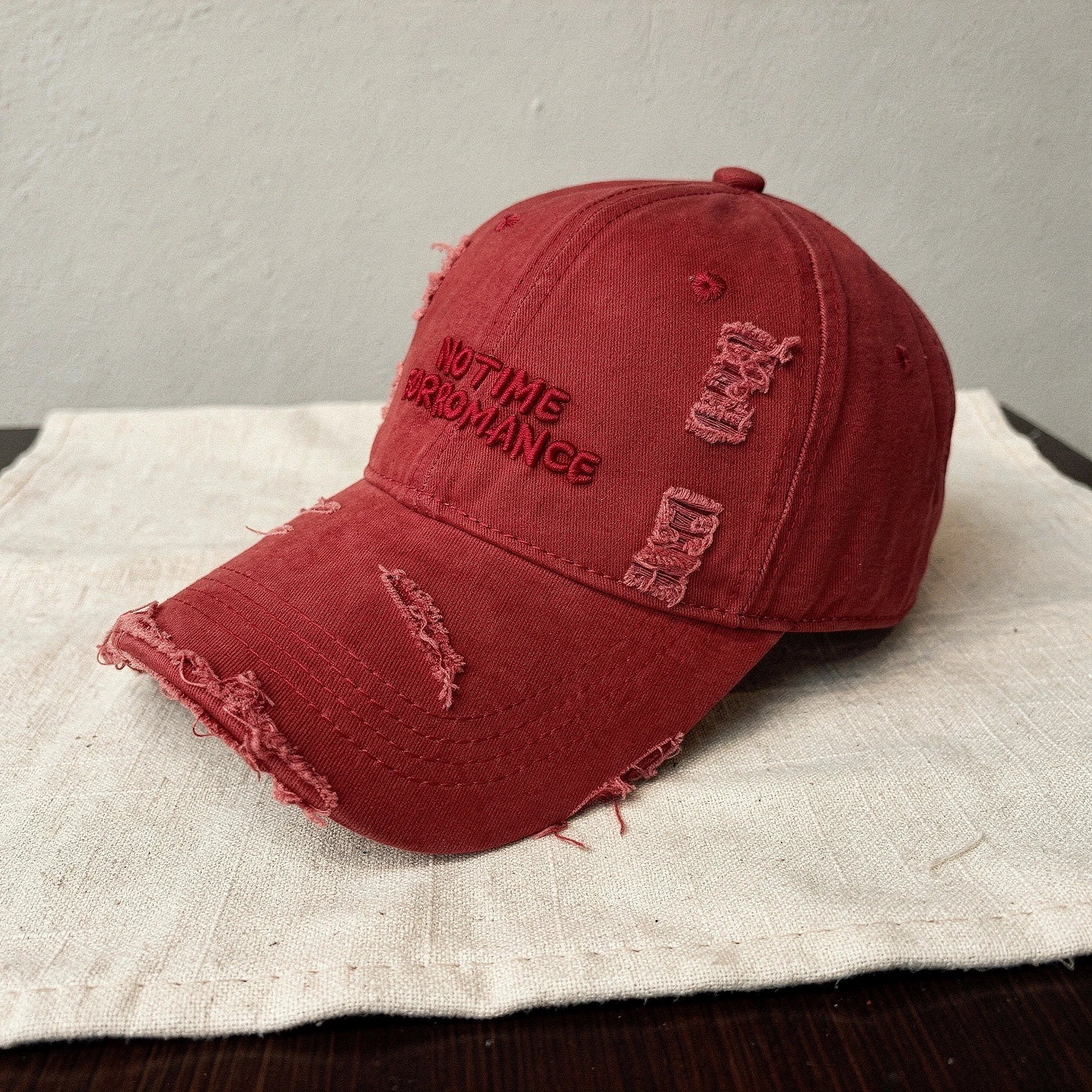 Distressed light blue baseball cap with a curved brim and adjustable strap, detailed view showcasing fabric texture and wear