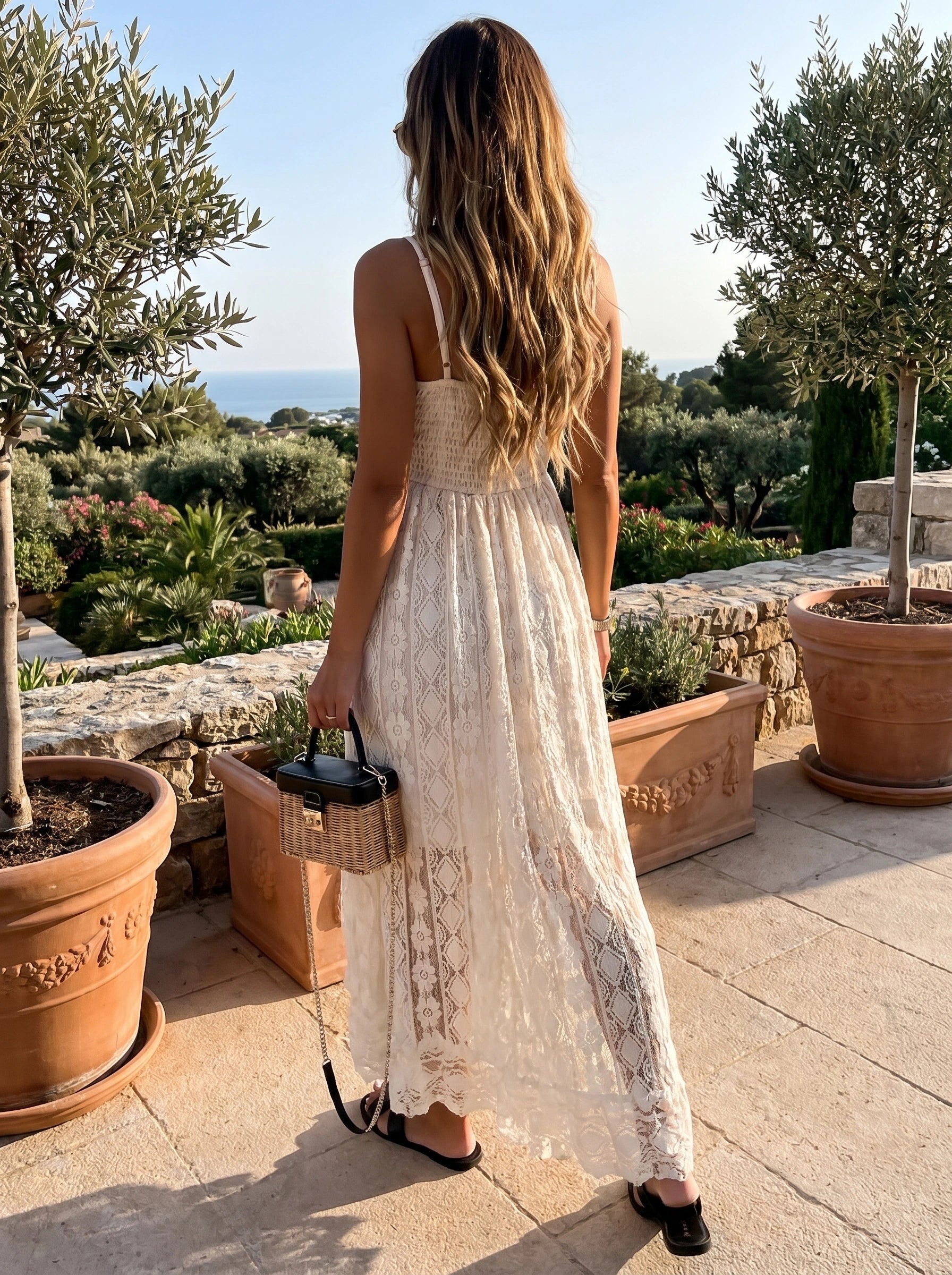 Front view of a model showing a women's flowy summer dress in soft pastel colors, styled for a beach vacation against a serene coastal background.