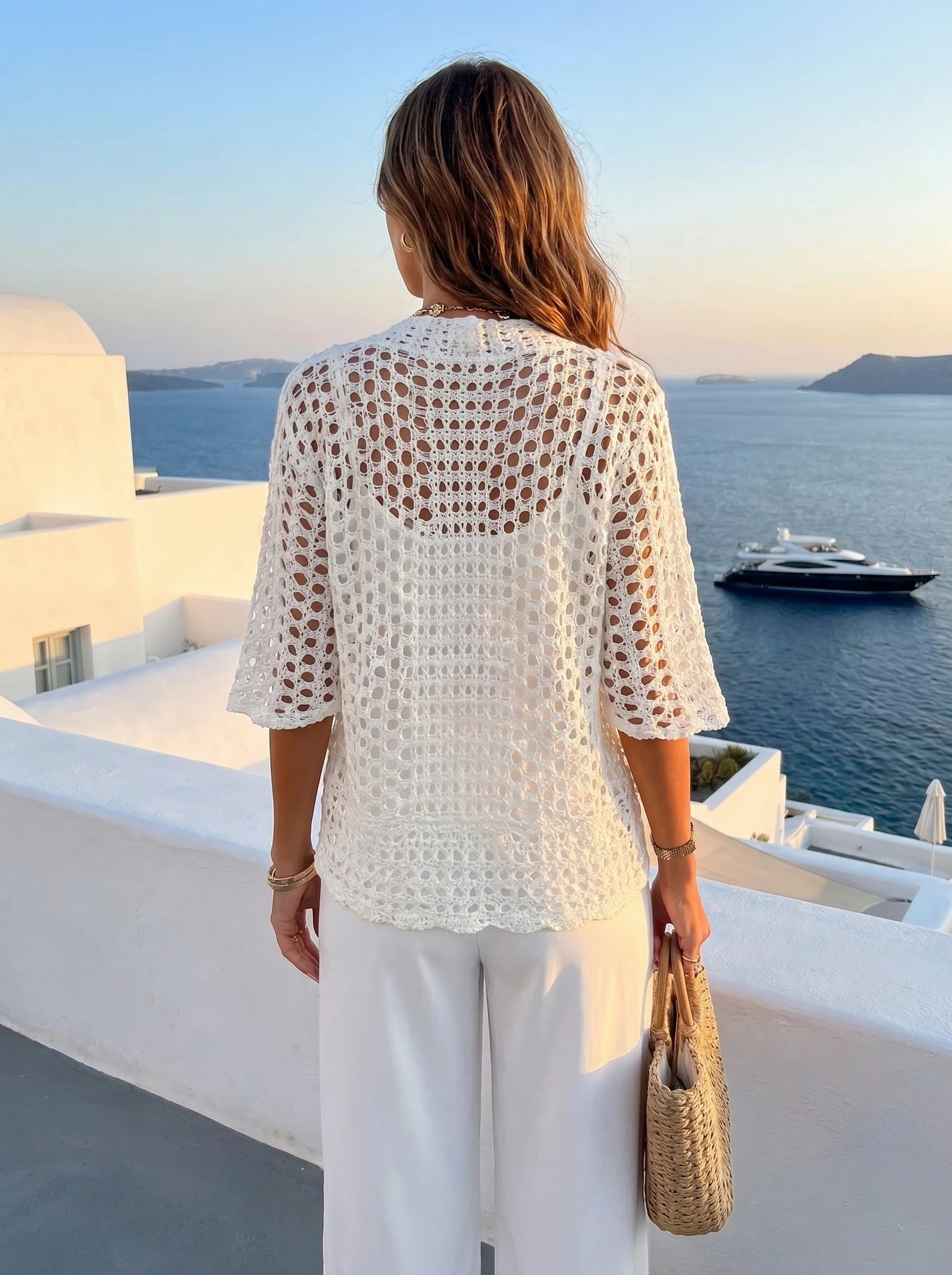 A model showcases a womens relaxed summer cardigan in a soft pastel hue, styled with high waisted trousers against a light, neutral background.
