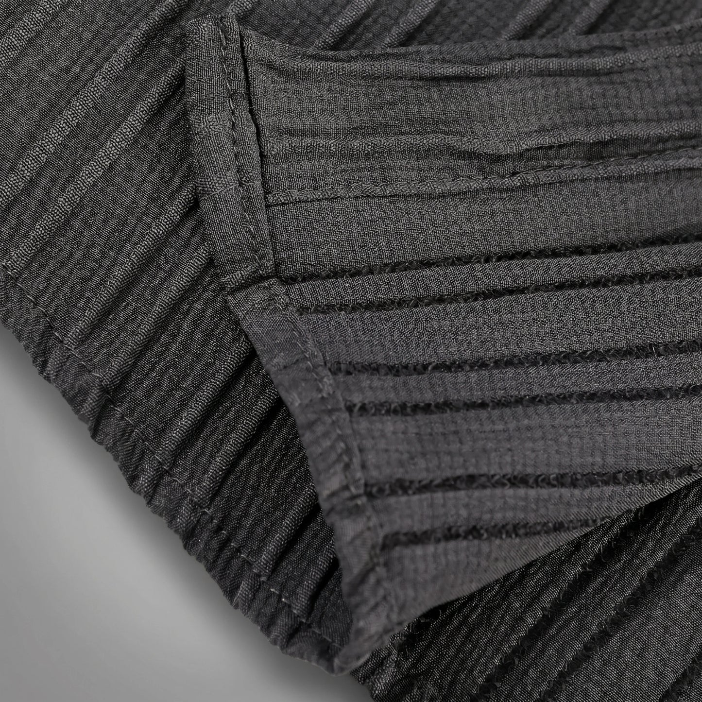 Close up view of the mens textured relaxed spring shirt showing intricate fabric details and stitching in a soft pastel color against a neutral background.