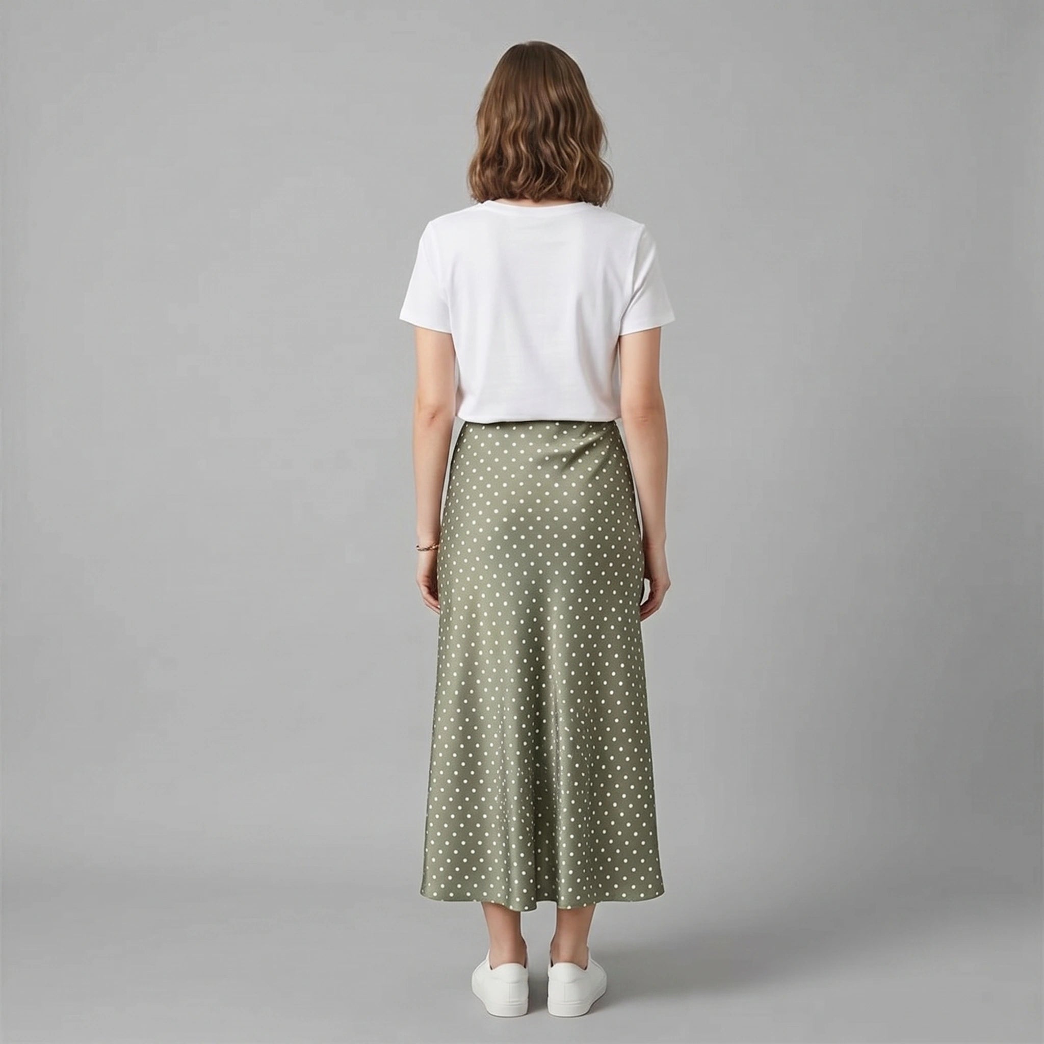 A model showcases a high waisted, playful polka dot midi skirt in a vibrant spring color, styled with a fitted top against a bright, airy background.