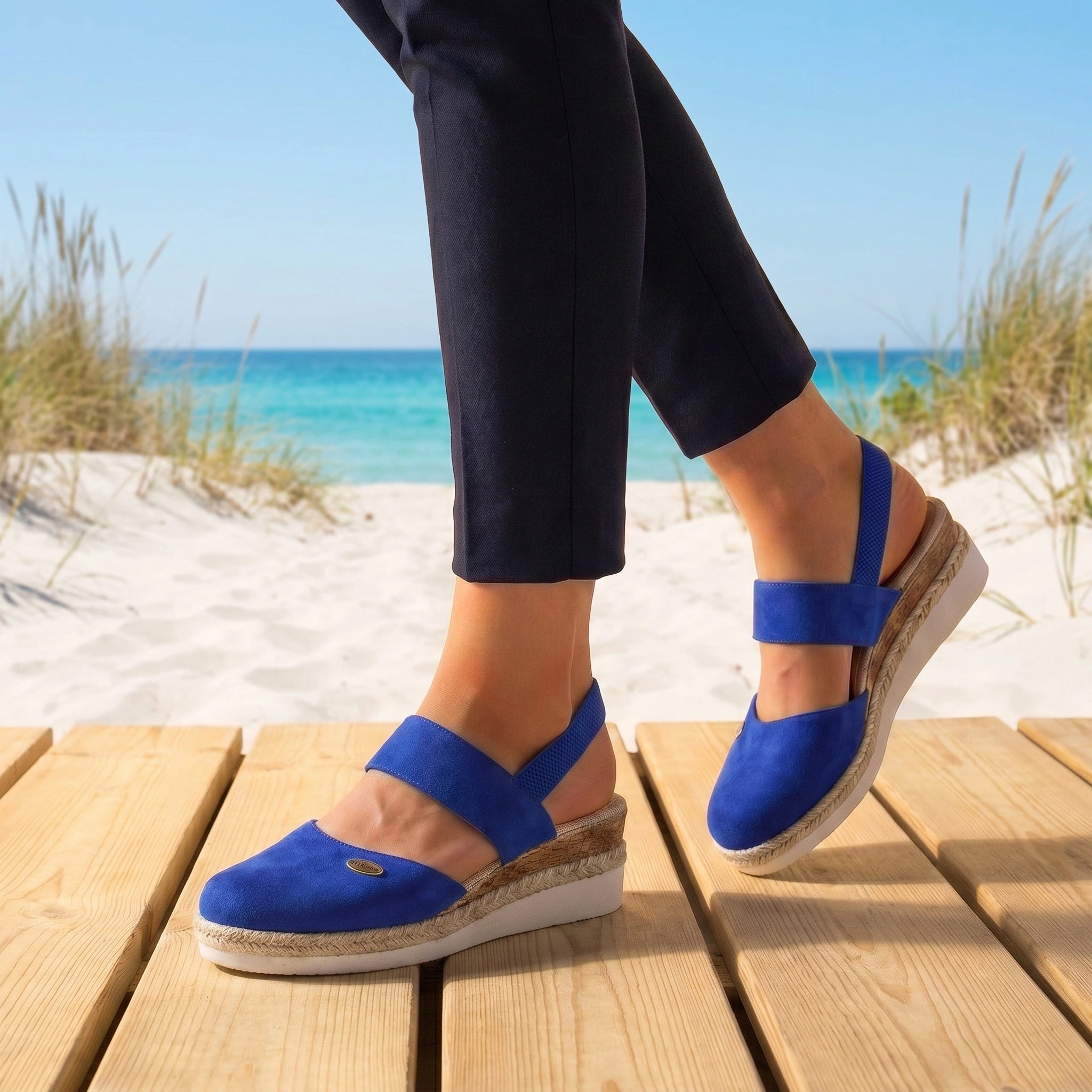 Back view of a model wearing comfortable summer sandals in a neutral tone, showing the construction details against a soft outdoor background.