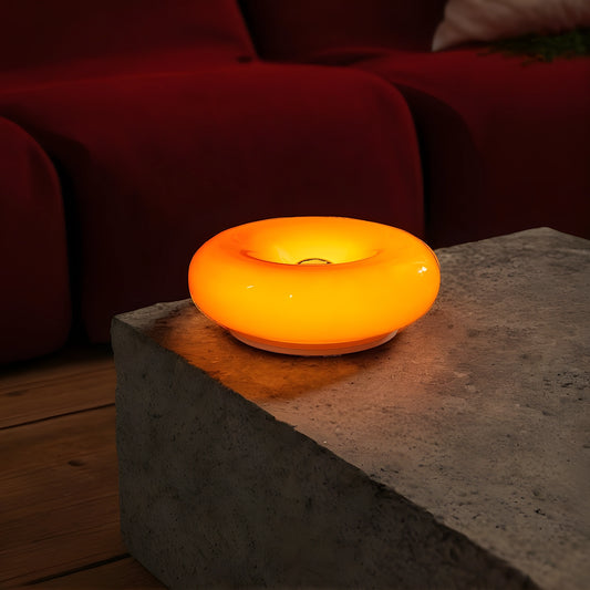 View of a sleek modern glass donut table lamp with an adjustable light feature, showcasing a minimalist design and clear glass material