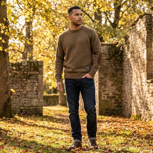Back view of the Mens Timeless Relaxed Elbow Patch Sweater in a neutral color, showing its construction details and relaxed fit against a soft backdrop.