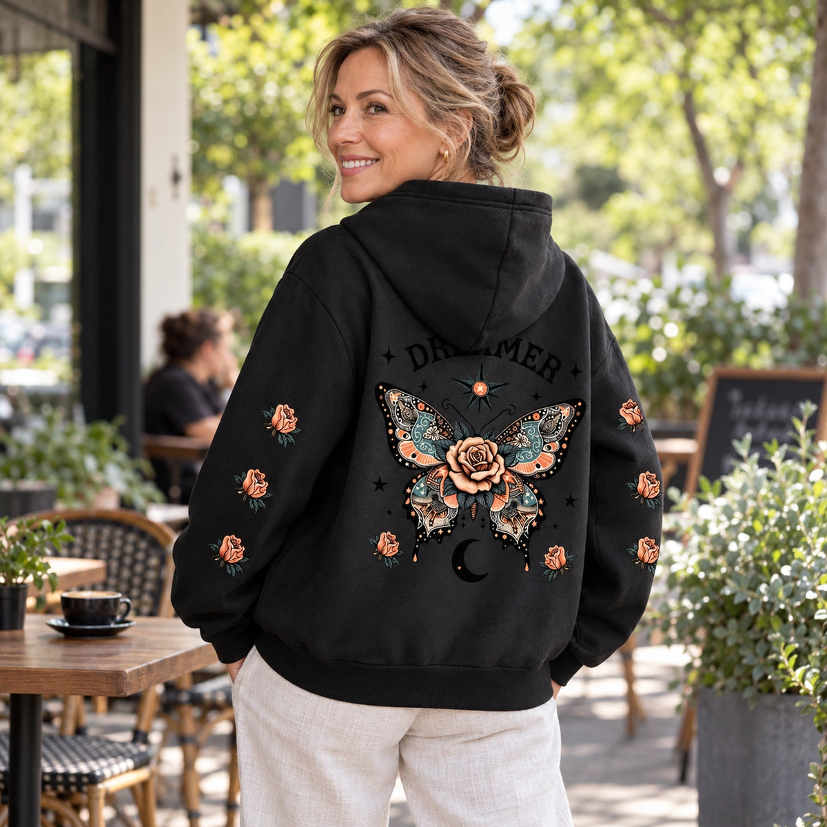 Black butterfly and rose print hoodie, rear view at a Melbourne cafe — view 8