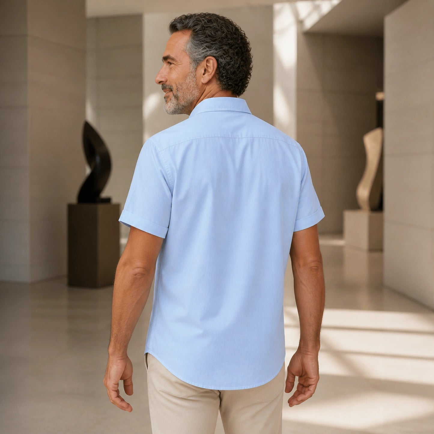 Rear three quarter view of a mature man wearing the blue Oxford shirt, showing back yoke, sleeves, side seams and — view 6
