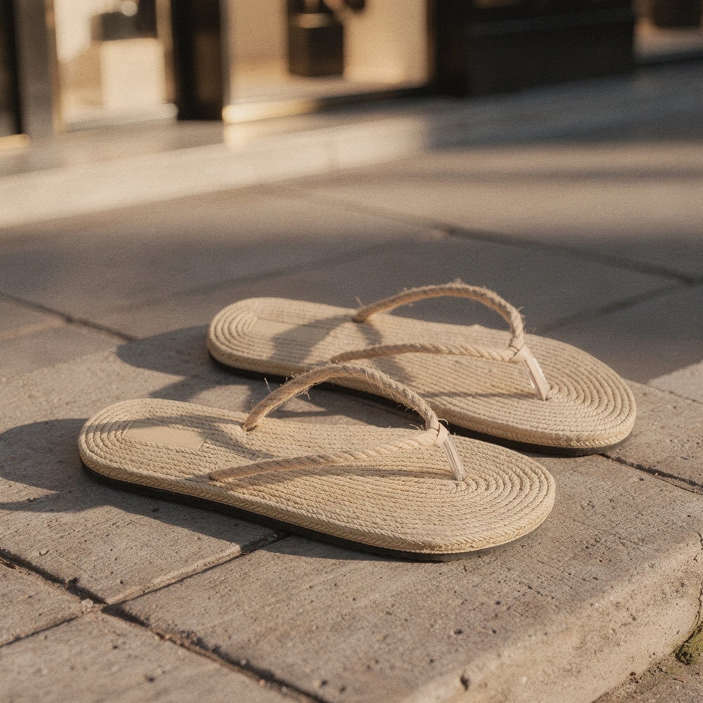 View of chic casual straw flip flop sandals in light tan with a woven texture and comfortable flat sole, perfect for summer wear