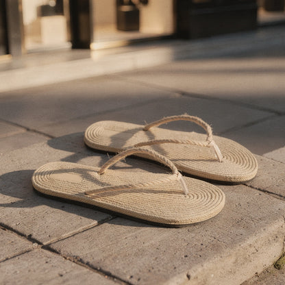 View of chic casual straw flip flop sandals in light tan with a woven texture and comfortable flat sole, perfect for summer wear
