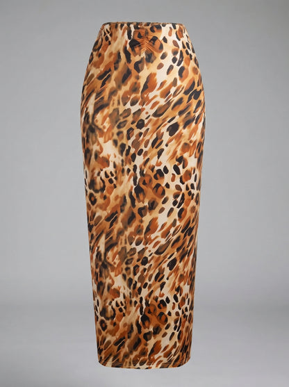 Back view of a model wearing a lightweight summer maxi skirt in a vibrant floral print, showing its high waisted design and construction details against a sunny outdoor backdrop.