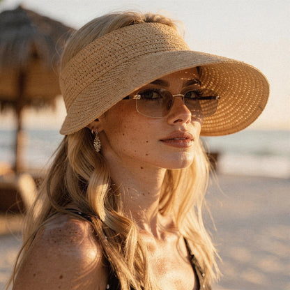 Light beige summer visor hat made of woven straw, featuring a wide brim and a decorative bow on the