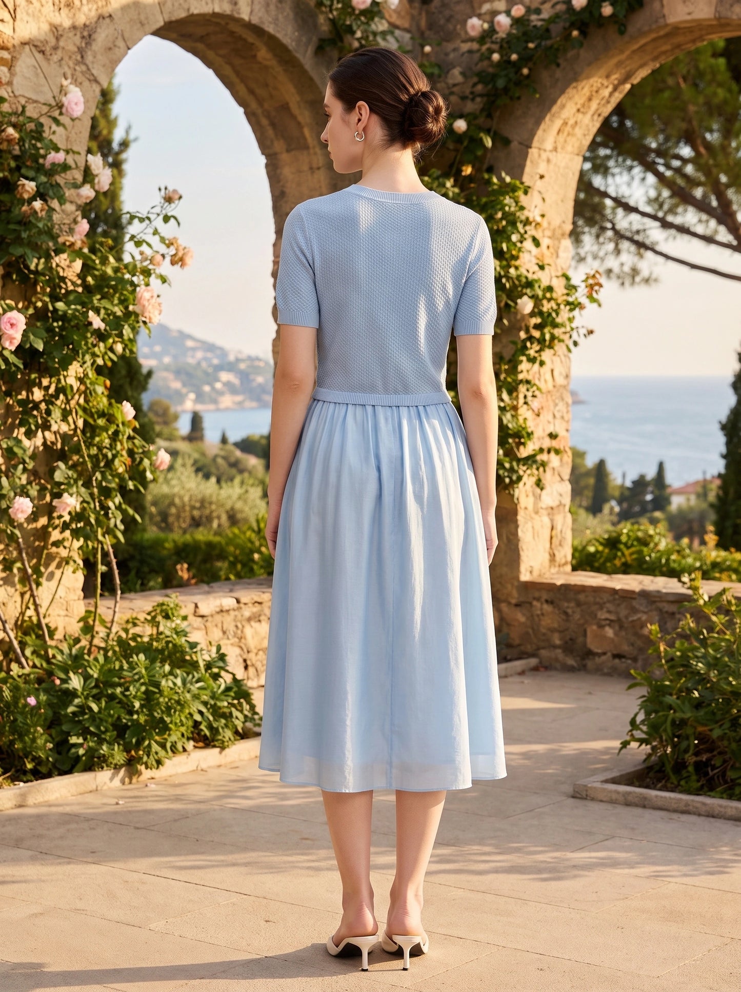 Back view of a model showing the Womens Fit and Flare Midi Dress in a soft pastel color, showing its tailored construction and flowing silhouette against a neutral background.