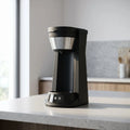 Sleek compact coffee maker with an intuitive control panel, showcasing a transparent water reservoir and a modern design