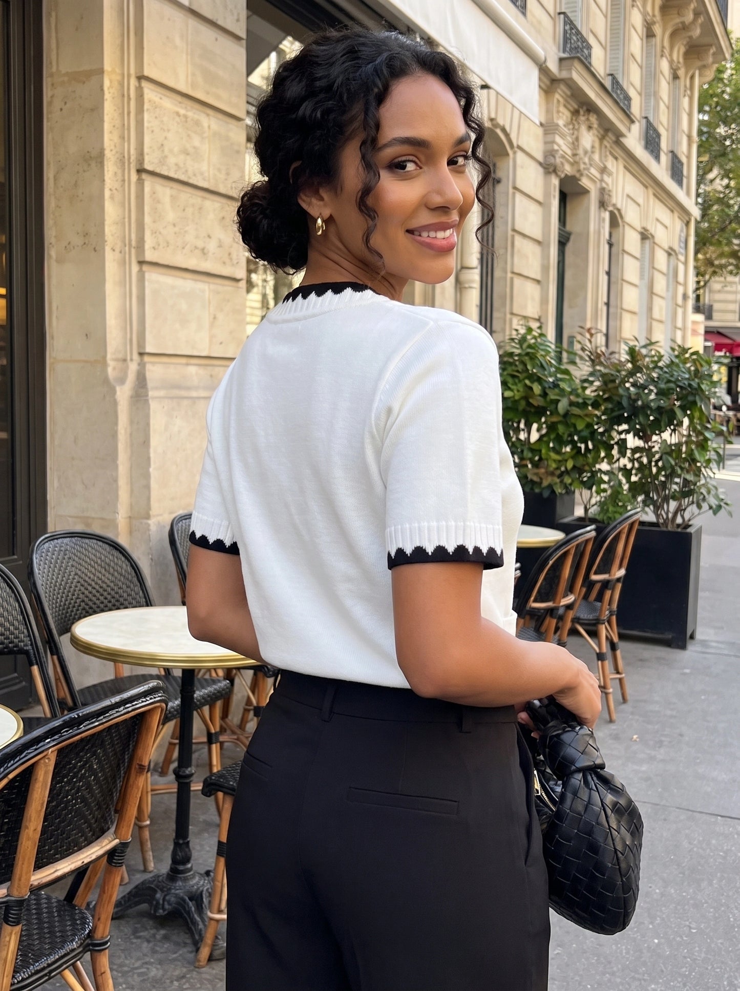 Front view of a model wearing a women's fitted summer cardigan in a soft pastel color, styled with high waisted trousers against a neutral background.