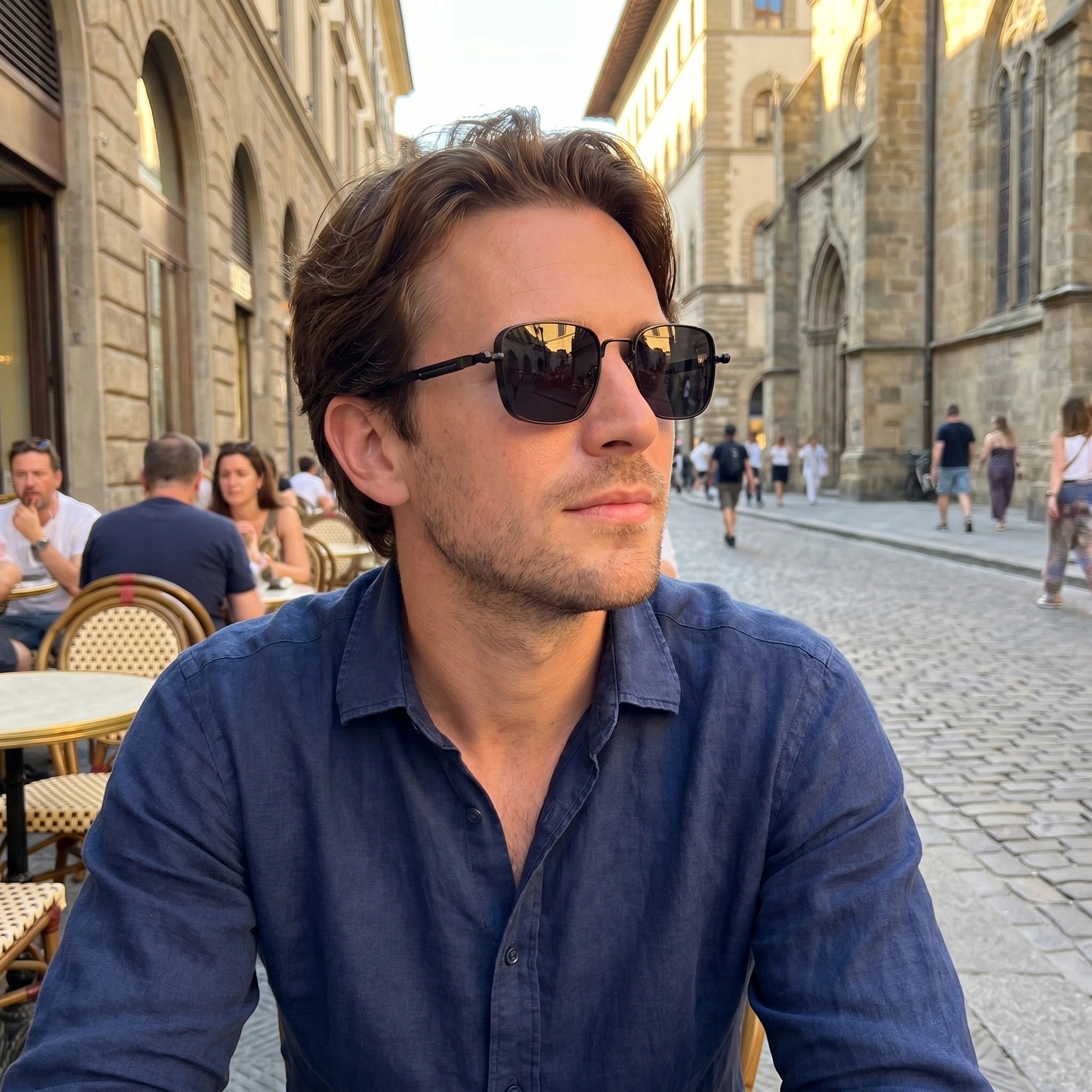 A model showcases sleek summer sunglasses paired with a light linen shirt and tailored shorts, set against a vibrant outdoor backdrop.