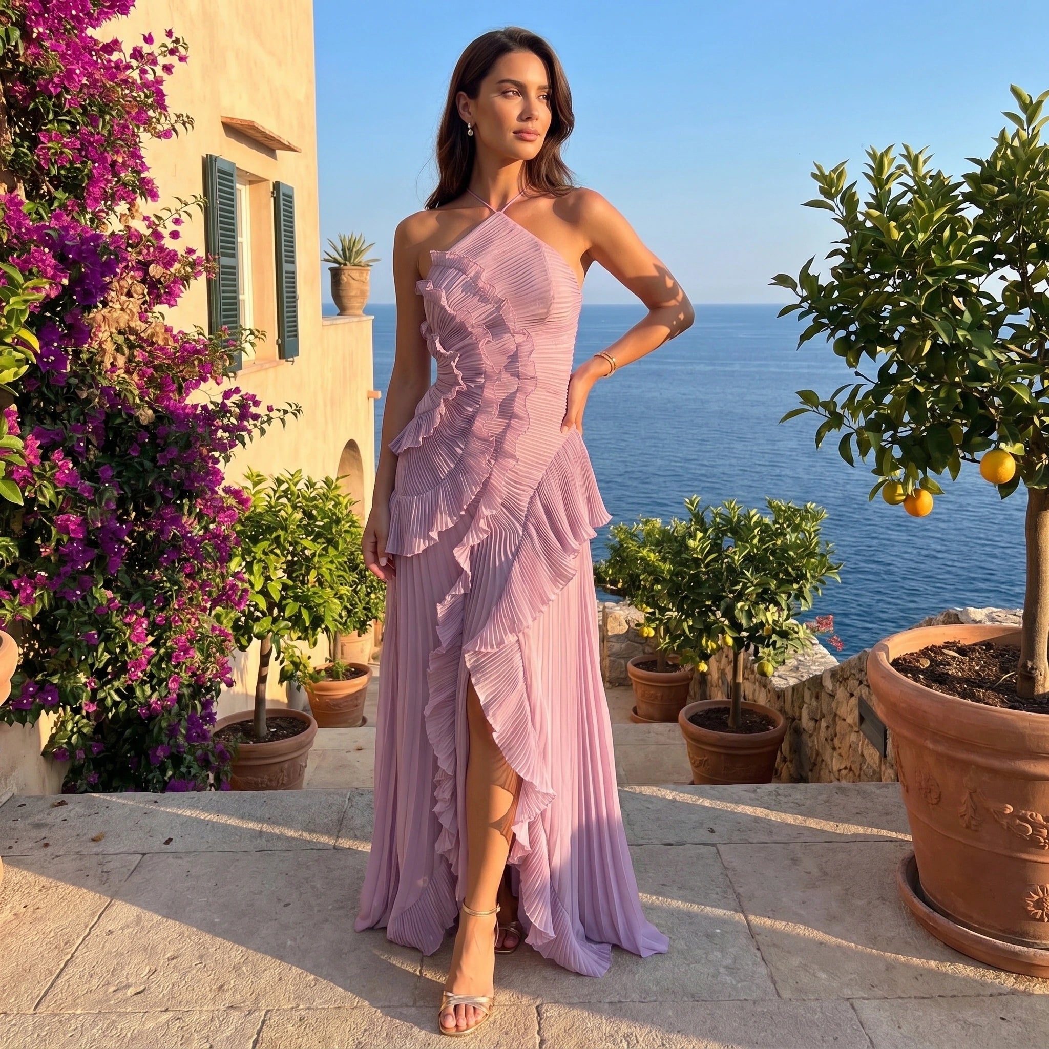 Back view of a model wearing a women's pleated maxi dress in soft blush, showing its flowing silhouette and intricate pleating details against a neutral backdrop.