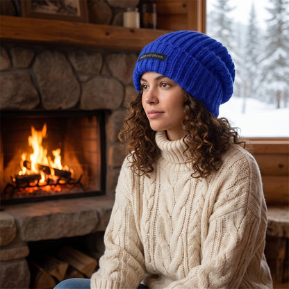 Front view of a model showing a women's cozy slouchy winter beanie in a soft knit, styled with a high waisted coat against a neutral backdrop.