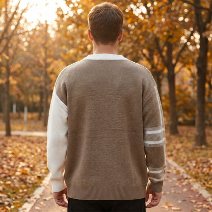 A model showcases a mens modern color block winter sweater in navy and gray, styled with dark jeans against a neutral backdrop.
