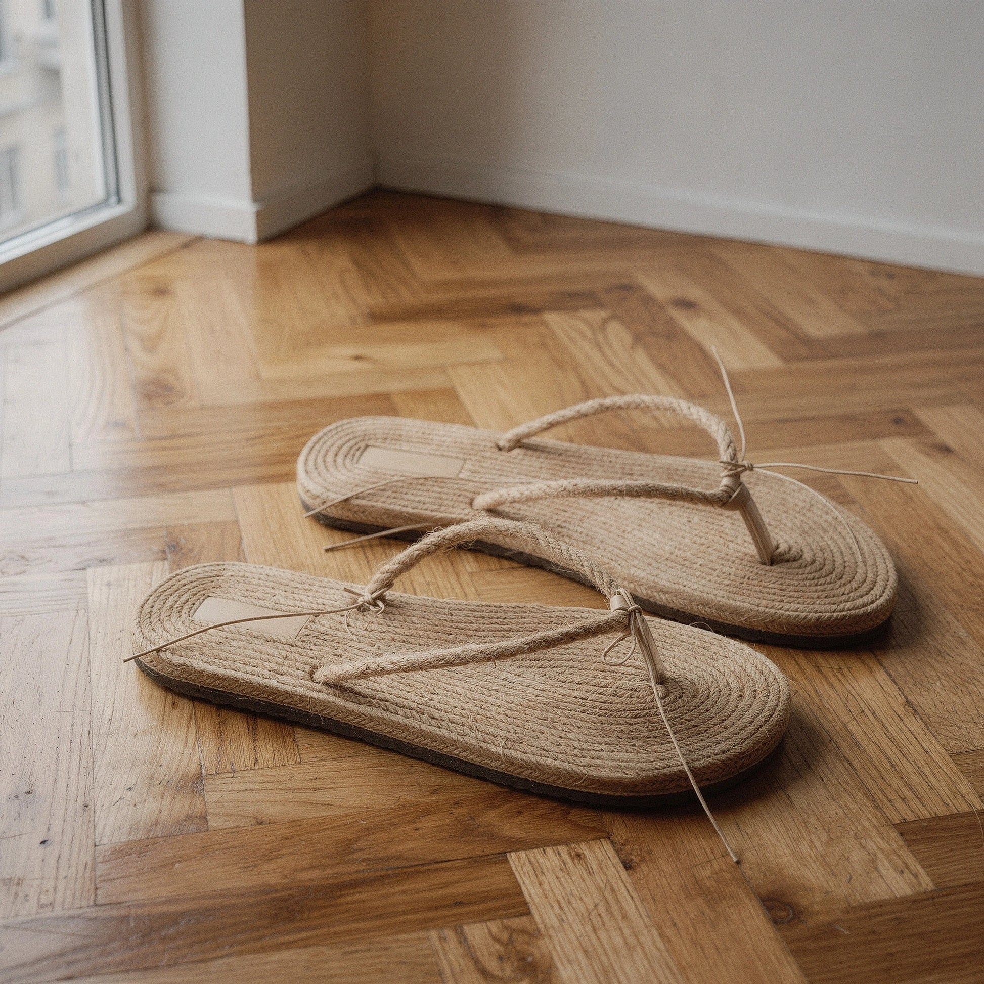 View of chic casual straw flip flop sandals in tan, featuring a comfortable footbed and woven strap design for summer wear