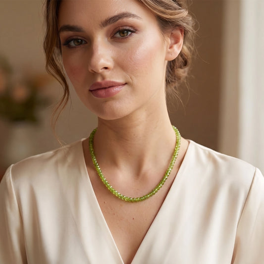 Close up of the Womens Classic Peridot Necklace showing its exquisite craftsmanship and vibrant green stones against a soft, neutral fabric background.