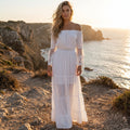 A model showcases the Womens Boho Effortless Summer Maxi Dress in a vibrant floral print, styled with sandals against a serene beach backdrop.