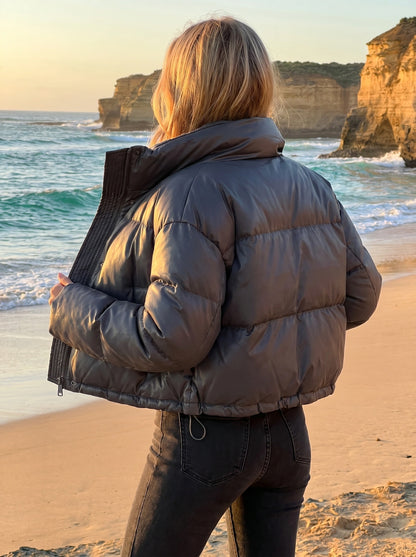 Back view of the women's cozy relaxed winter jacket in a soft gray hue, showing its construction details against a neutral backdrop.