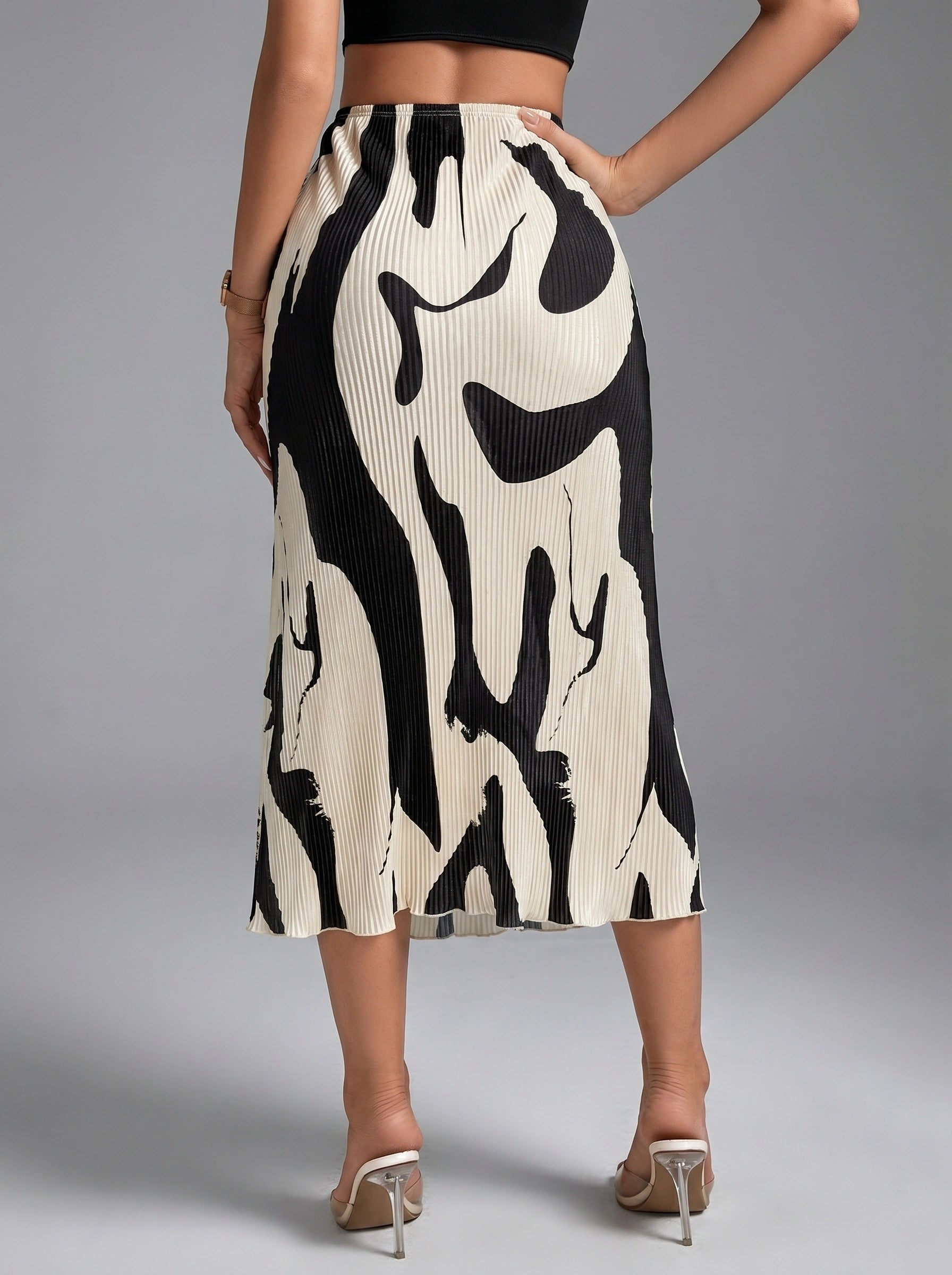 Back view of a model wearing a high waisted, artsy sophisticated autumn midi skirt in rich hues, showing intricate construction details against a neutral backdrop.