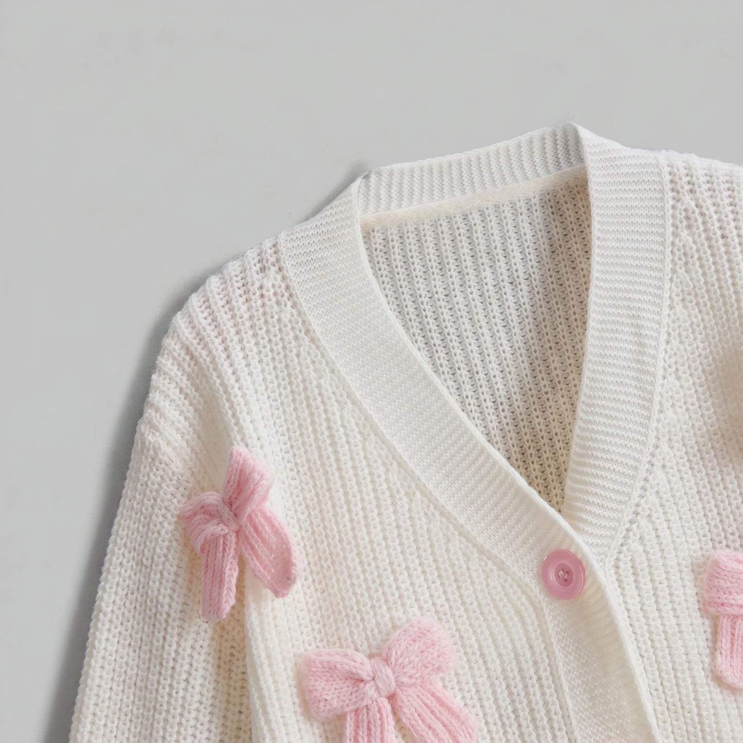 Back view of the Womens Whimsical Cozy Spring Cardigan in soft pastel colors, showing its intricate stitching and relaxed fit against a light, neutral background.