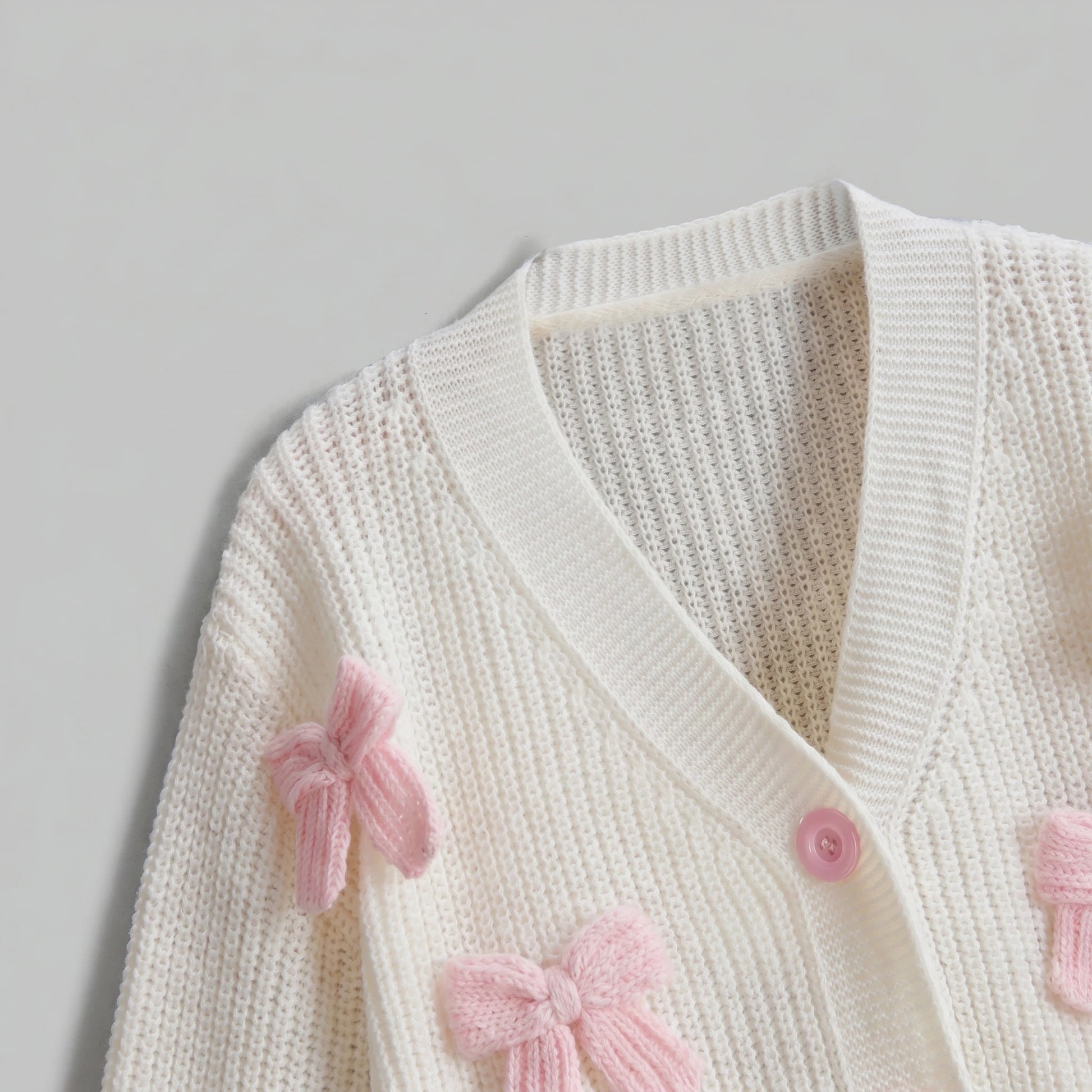 Back view of the Womens Whimsical Cozy Spring Cardigan in soft pastel colors, showing its intricate stitching and relaxed fit against a light, neutral background.