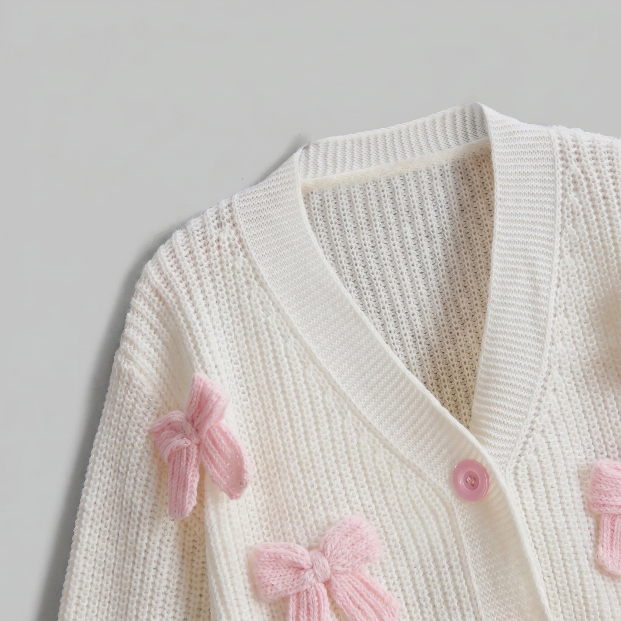 Back view of the Womens Whimsical Cozy Spring Cardigan in soft pastel colors, showing its intricate stitching and relaxed fit against a light, neutral background.