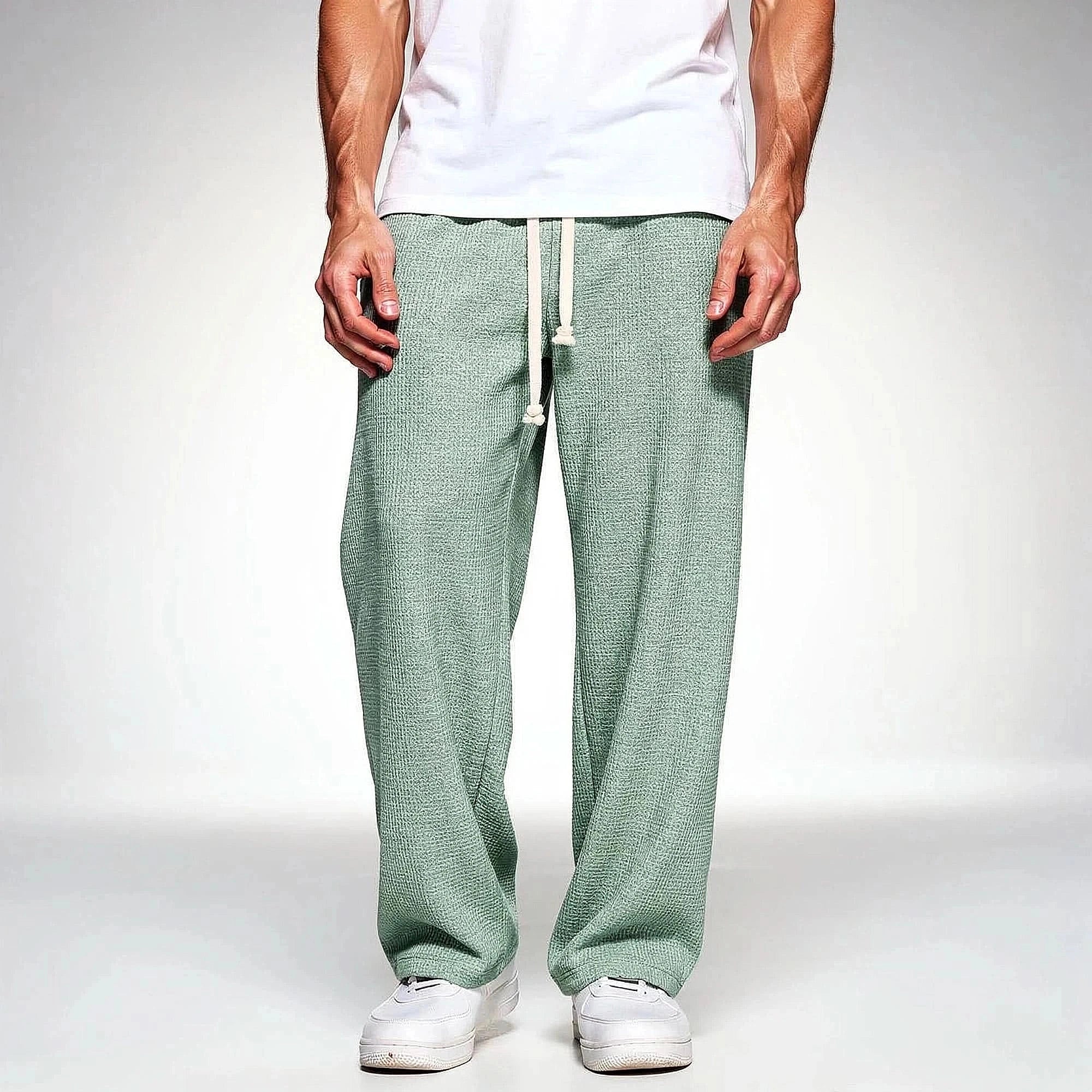 View of relaxed fit pants in soft beige fabric, featuring an elastic waistband and pockets