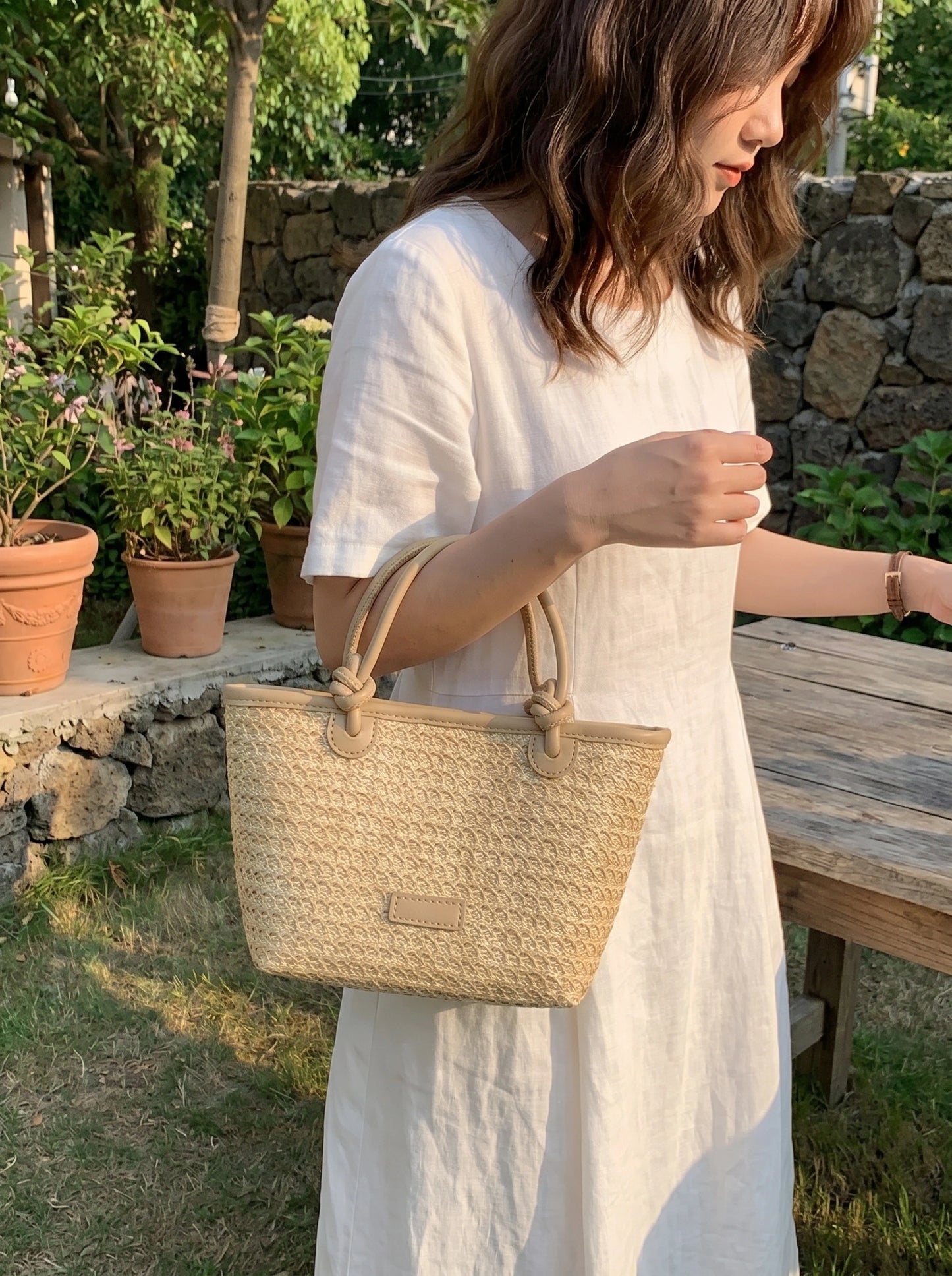 A model showcases the Womens Woven Summer Tote, styled with a light, breezy outfit against a bright outdoor background, perfect for beach outings.