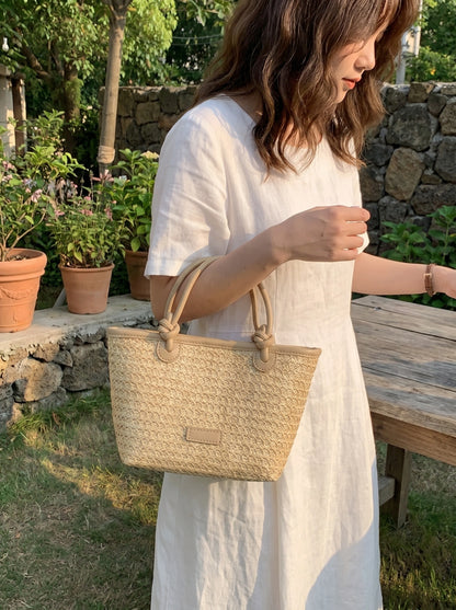 A model showcases the Womens Woven Summer Tote, styled with a light, breezy outfit against a bright outdoor background, perfect for beach outings.