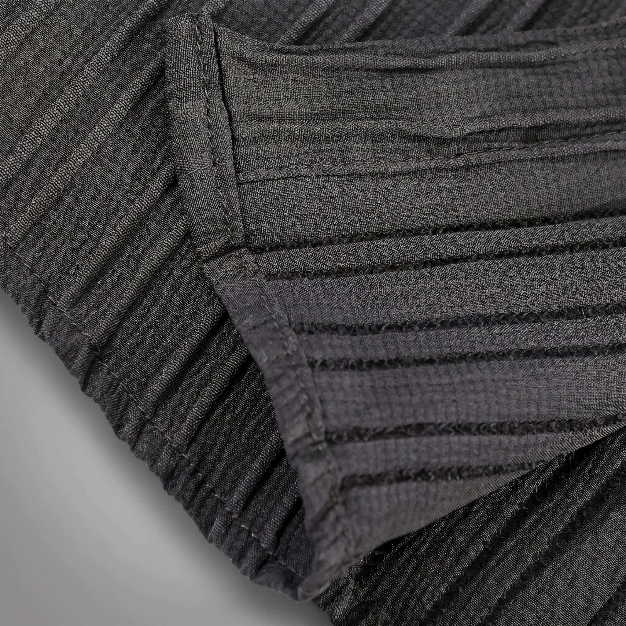 Close up view of the mens textured relaxed spring shirt showing intricate fabric details and stitching in a soft pastel color against a neutral background.