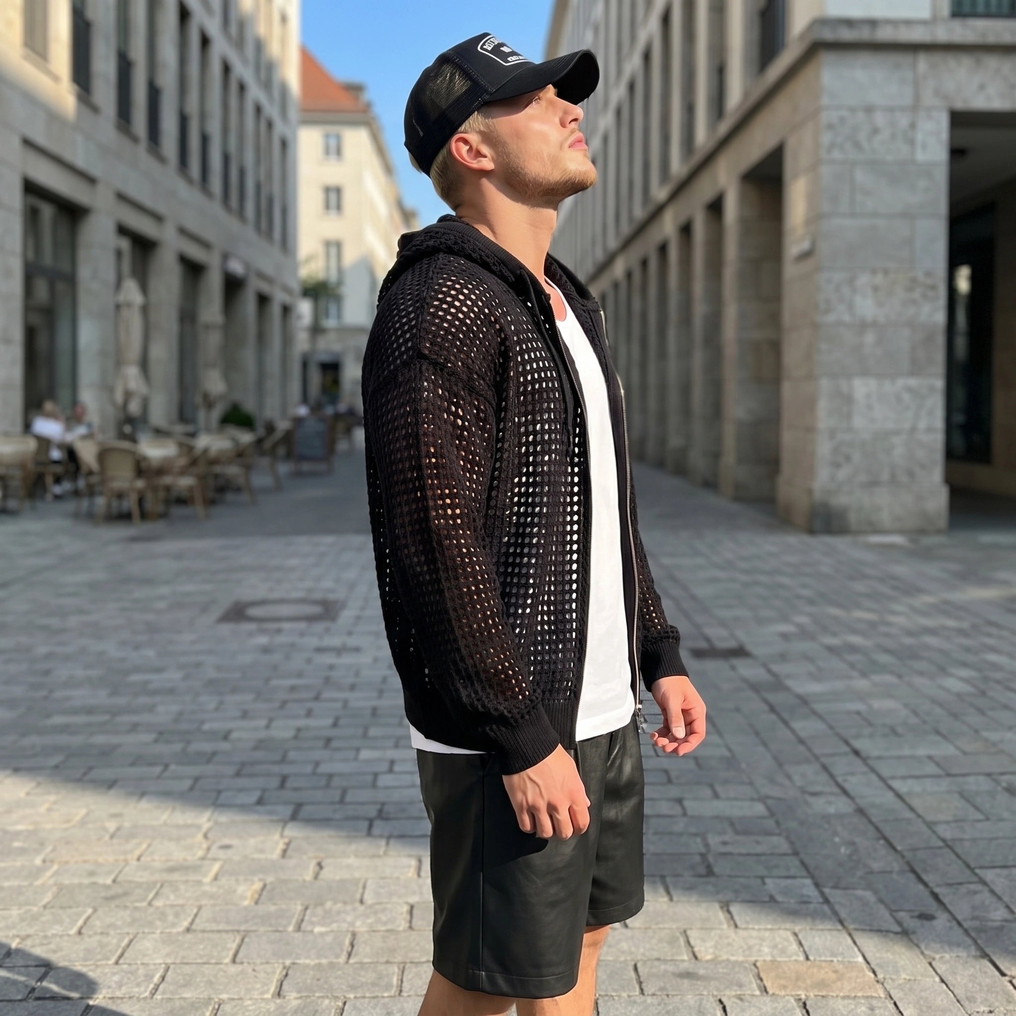A model showcases a mens casual lightweight summer hoodie in a soft gray color, styled with accessories against a minimalistic urban background.