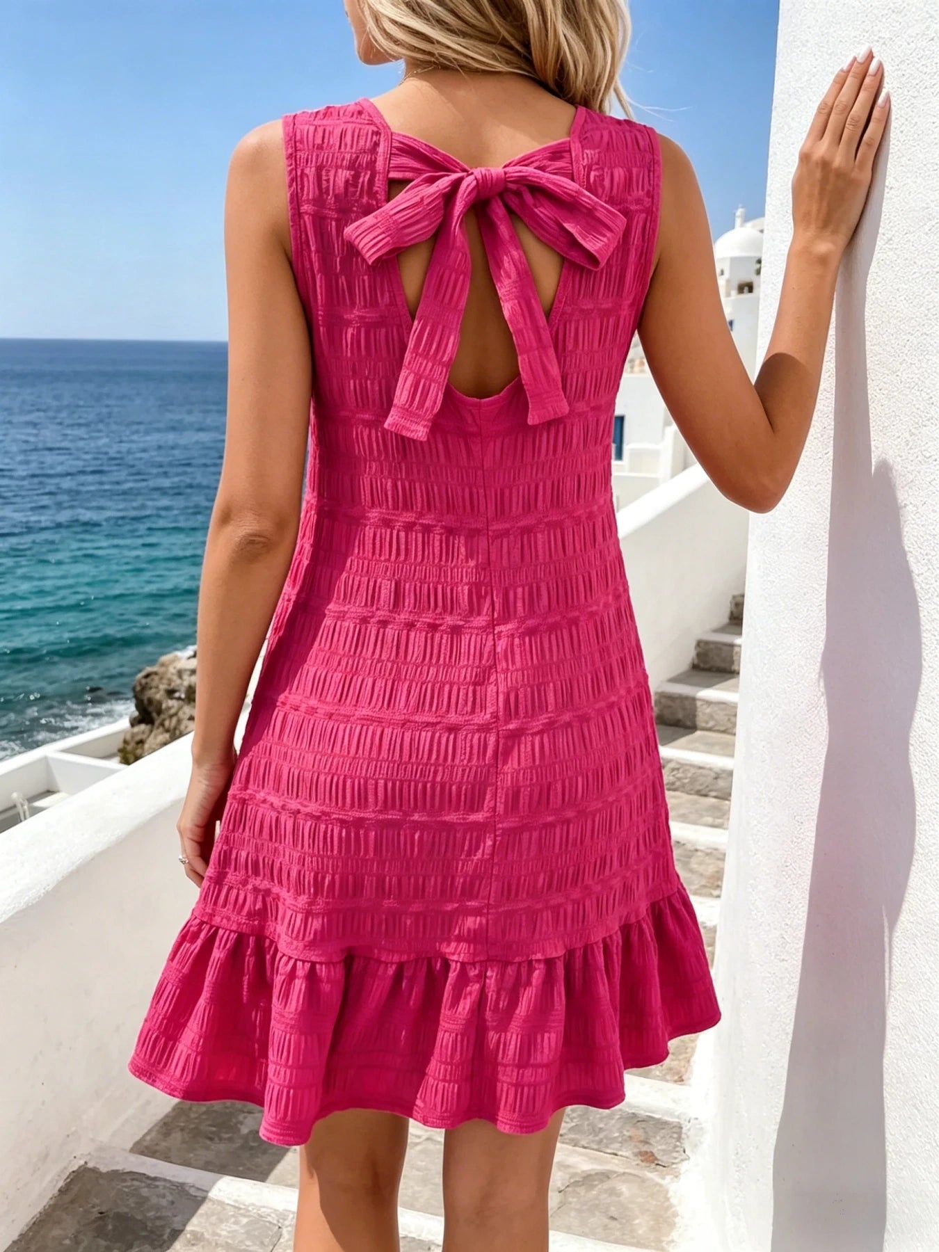 View of a textured flirty summer mini dress in light pink, featuring a fitted bodice and flared skirt
