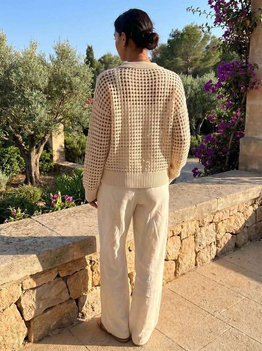Back view of a model wearing a women's hollow knit autumn cardigan in a warm beige color, showing intricate knit construction and sophisticated design details.