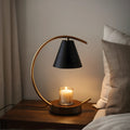 View of a sculptural dimmable candle warmer table lamp in earthy tones, featuring a textured ceramic base and a warm glow