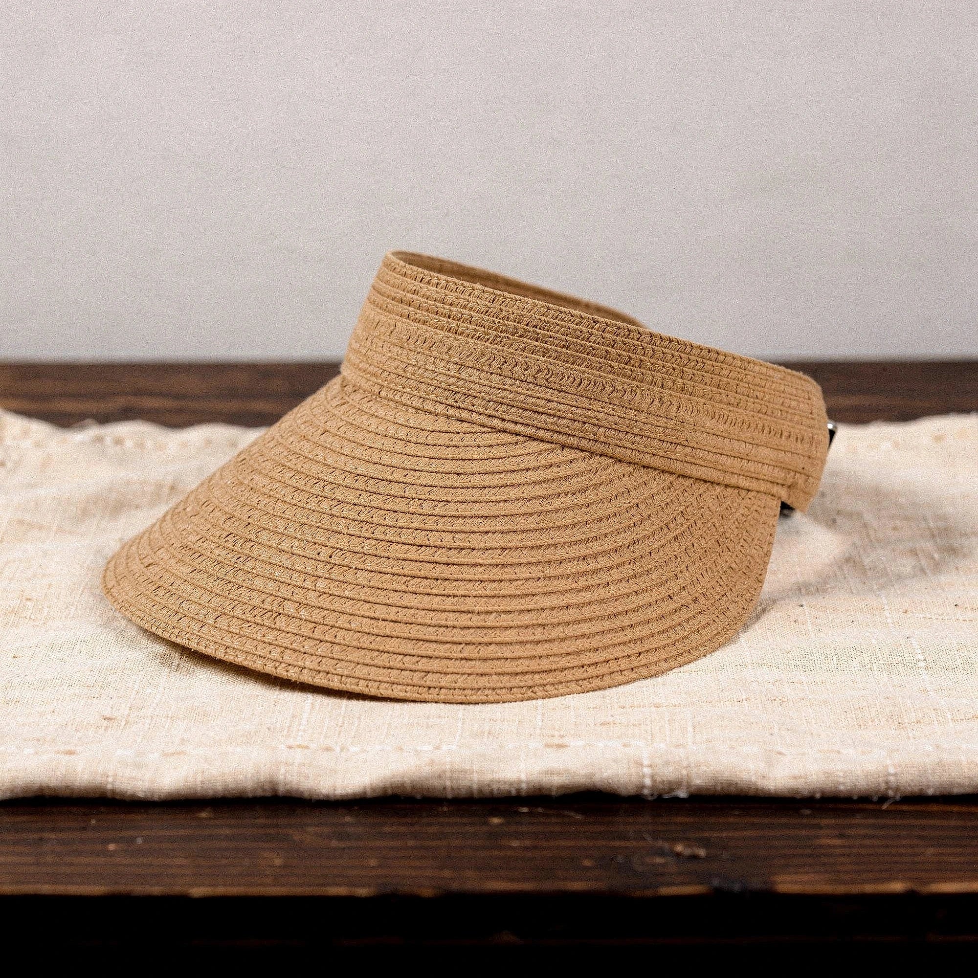 Light beige summer visor hat with a wide brim and textured woven material, detailed view showcasing the stitching and inner lining