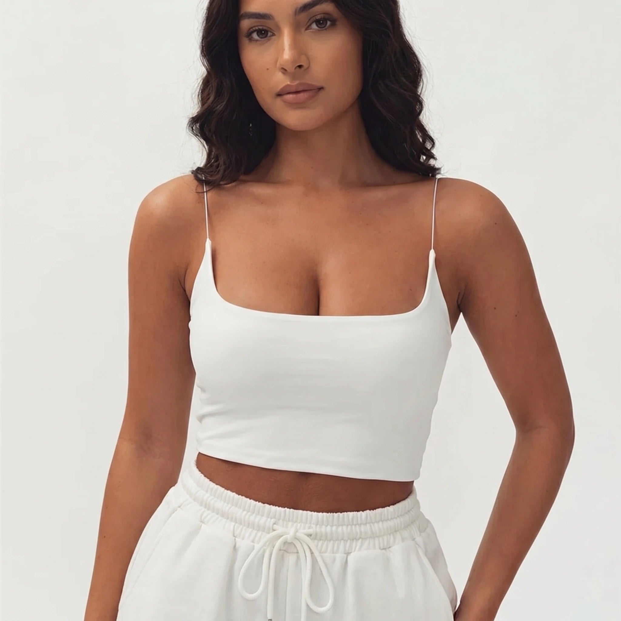 A model showcases the Womens Effortless Seamless Summer Crop Top in a colorful, styled with high waisted shorts against a bright, summery background.
