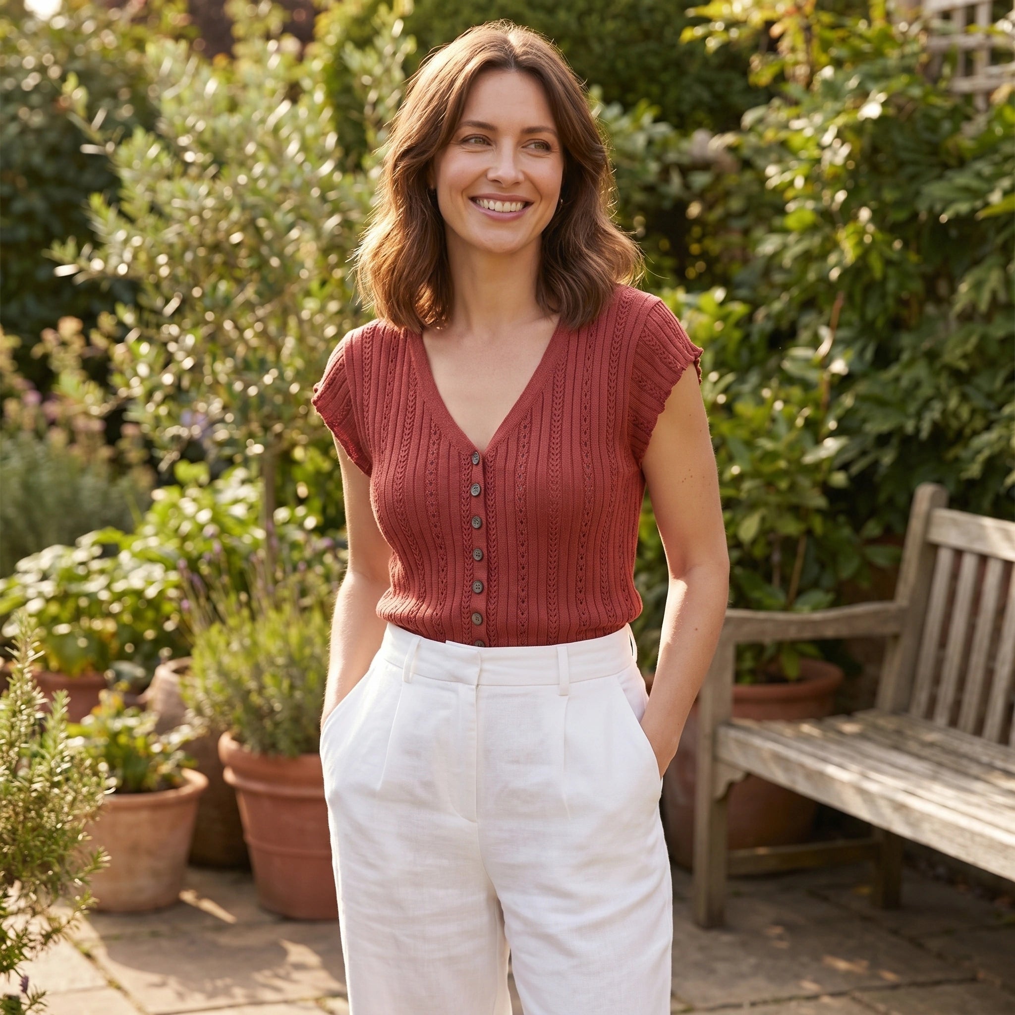 Front view of a model wearing a women's relaxed summer sweater in a soft pastel color, paired with high waisted shorts against a bright outdoor background.
