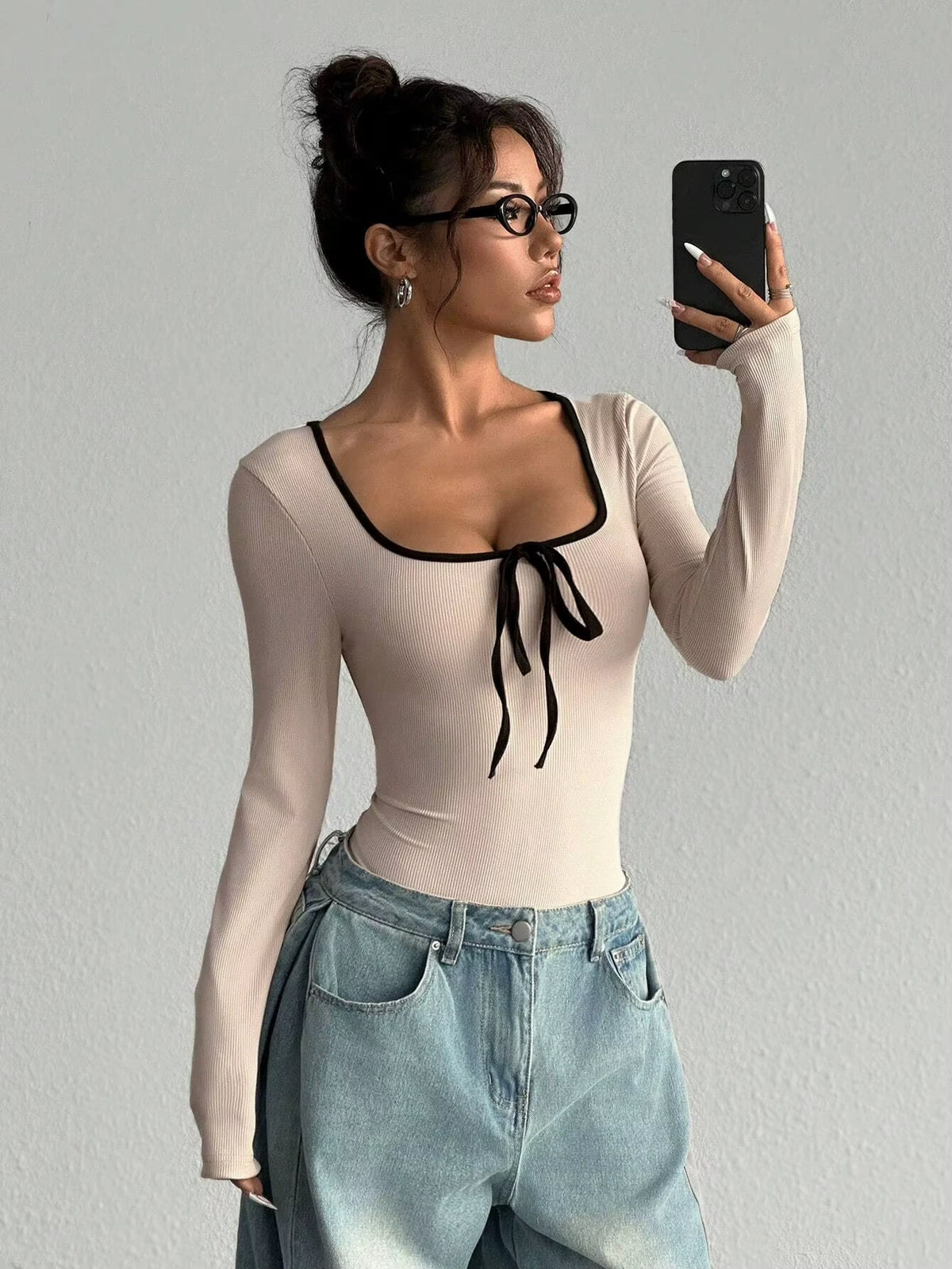 Woman wearing a beige long sleeve bodysuit with black bowknot and color block design — view 10 — view 10