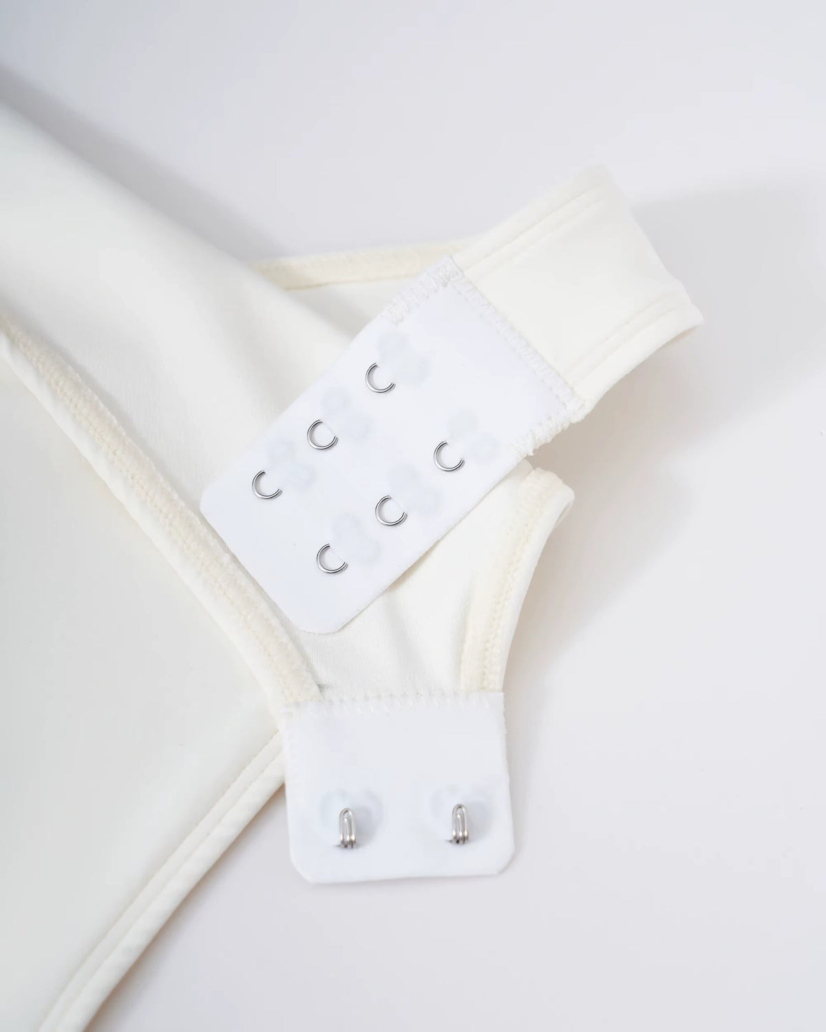 Close up of off white bodysuit with hook and eye closure detail — view 11 — view 11