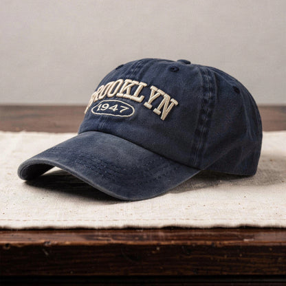 View of a navy blue cap featuring intricate white embroidery, made from soft cotton, showcasing a casual chic style