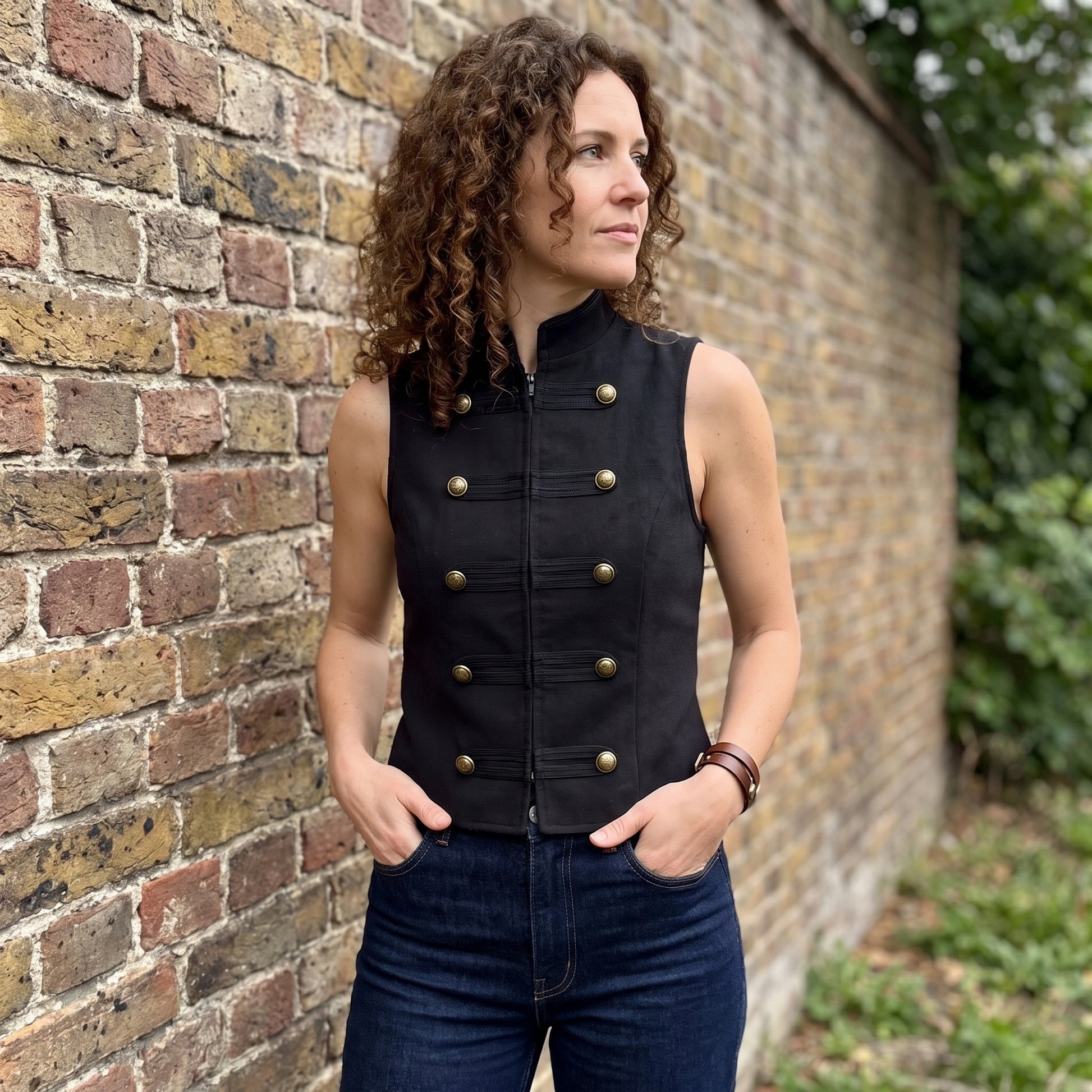 A model showcases the Womens Sleek Spring Top in Black, styled with high waisted trousers against a minimalist backdrop.