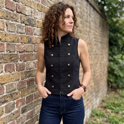 A model showcases the Womens Sleek Spring Top in Black, styled with high waisted trousers against a minimalist backdrop.