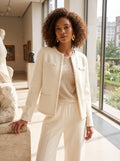 Back view of a model wearing a women's soft wool jacket in a neutral color, showing its tailored construction and sophisticated design against a minimalist backdrop.