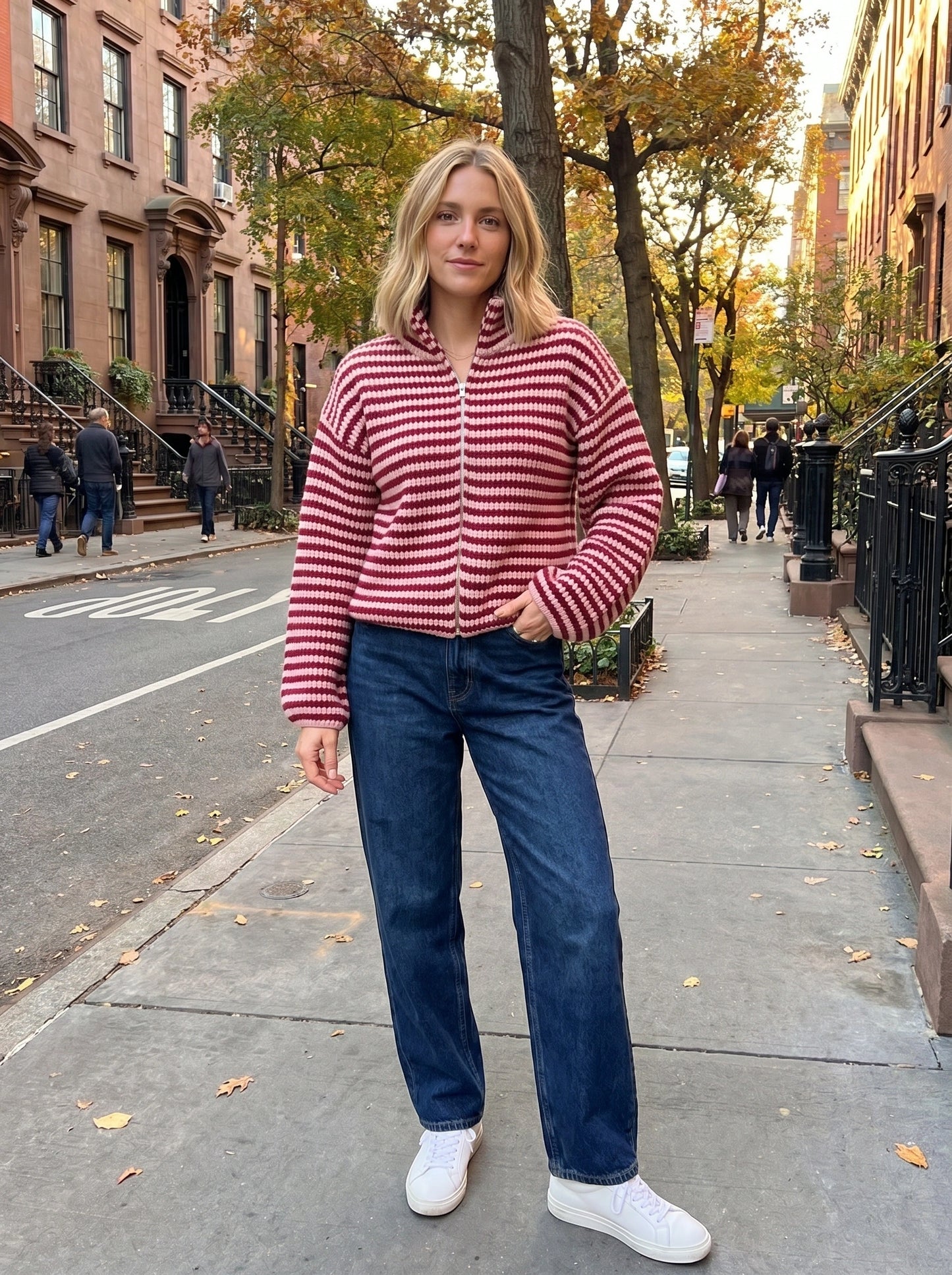 A model showcases a womens relaxed striped autumn cardigan in warm hues, styled with high waisted jeans and ankle boots against a neutral background.