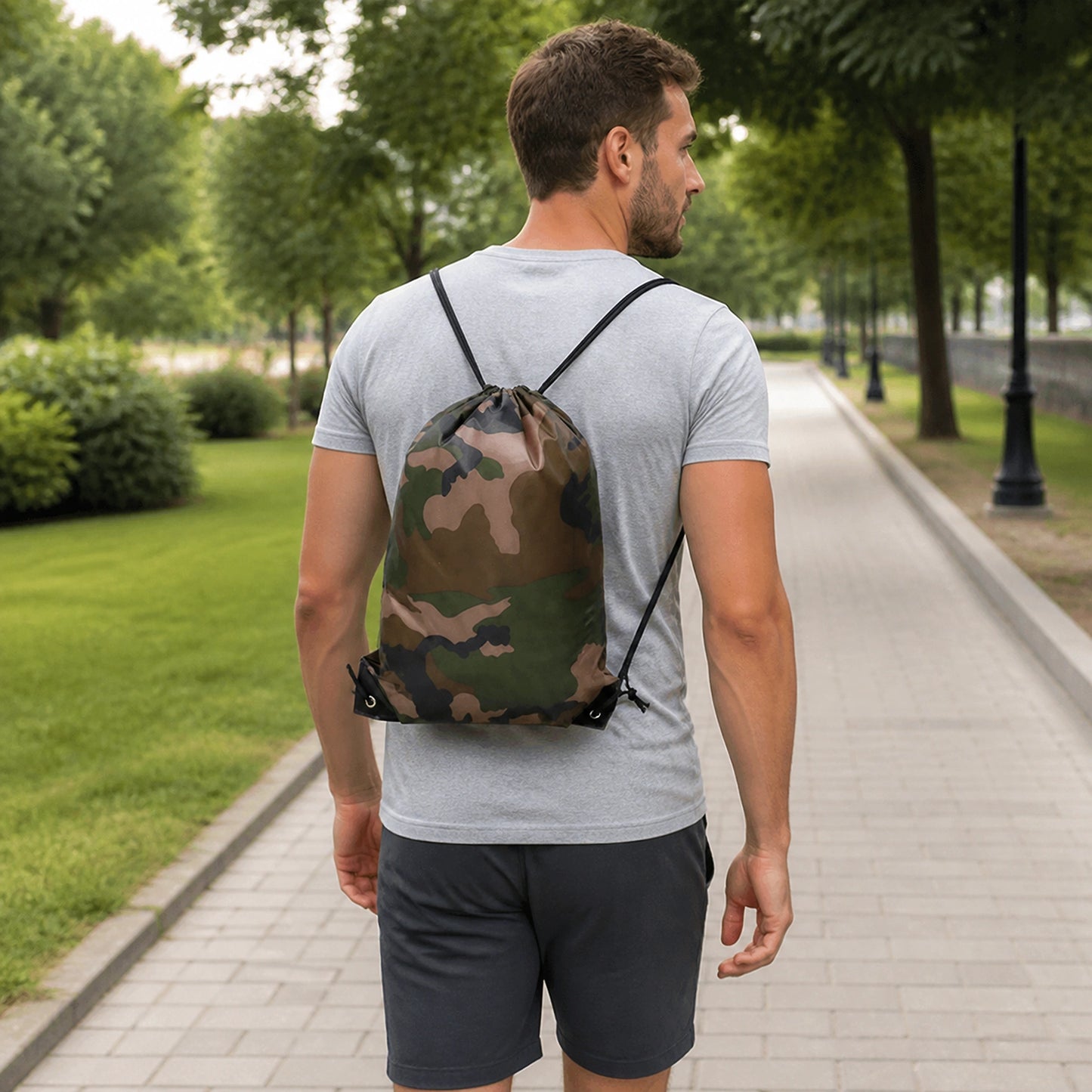 Adult wearing woodland camouflage drawstring backpack in a modern city setting — view 4