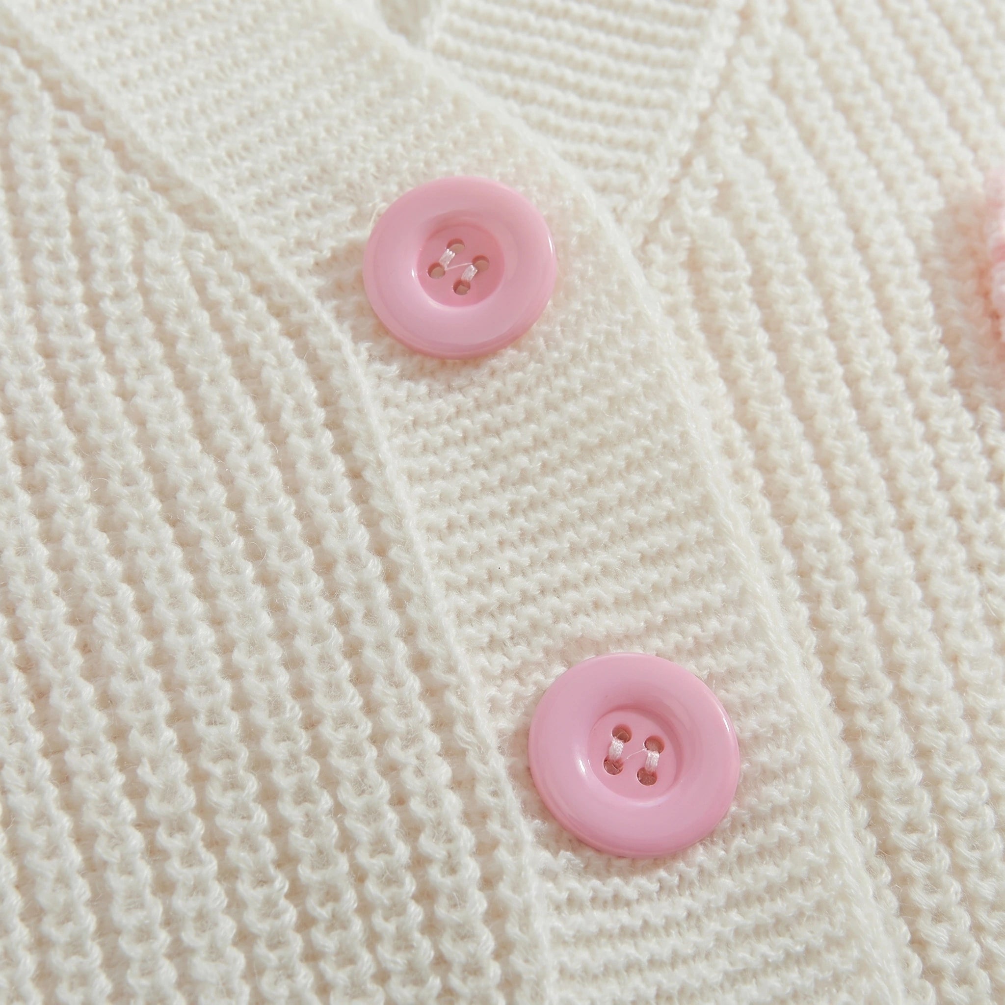 Close up of the Women's Whimsical Cozy Spring Cardigan showing the soft fabric texture and intricate stitching in a light pastel color.